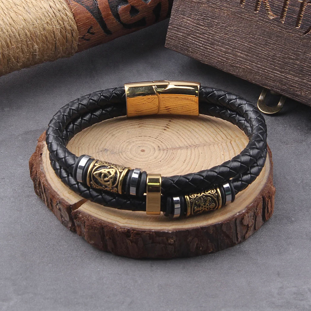 Dubbelflätat svart läderarmband med små guldfärgade vikingasmycken – vegvisir och triquetra