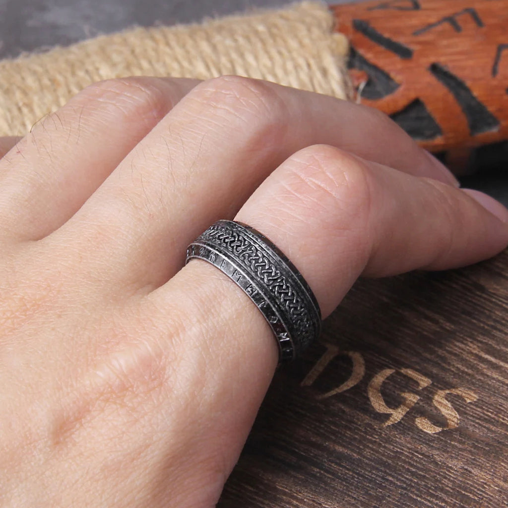 Gråsvart ring tillverkad av rostfritt stål, smyckad med vikingaknutar och runtecken