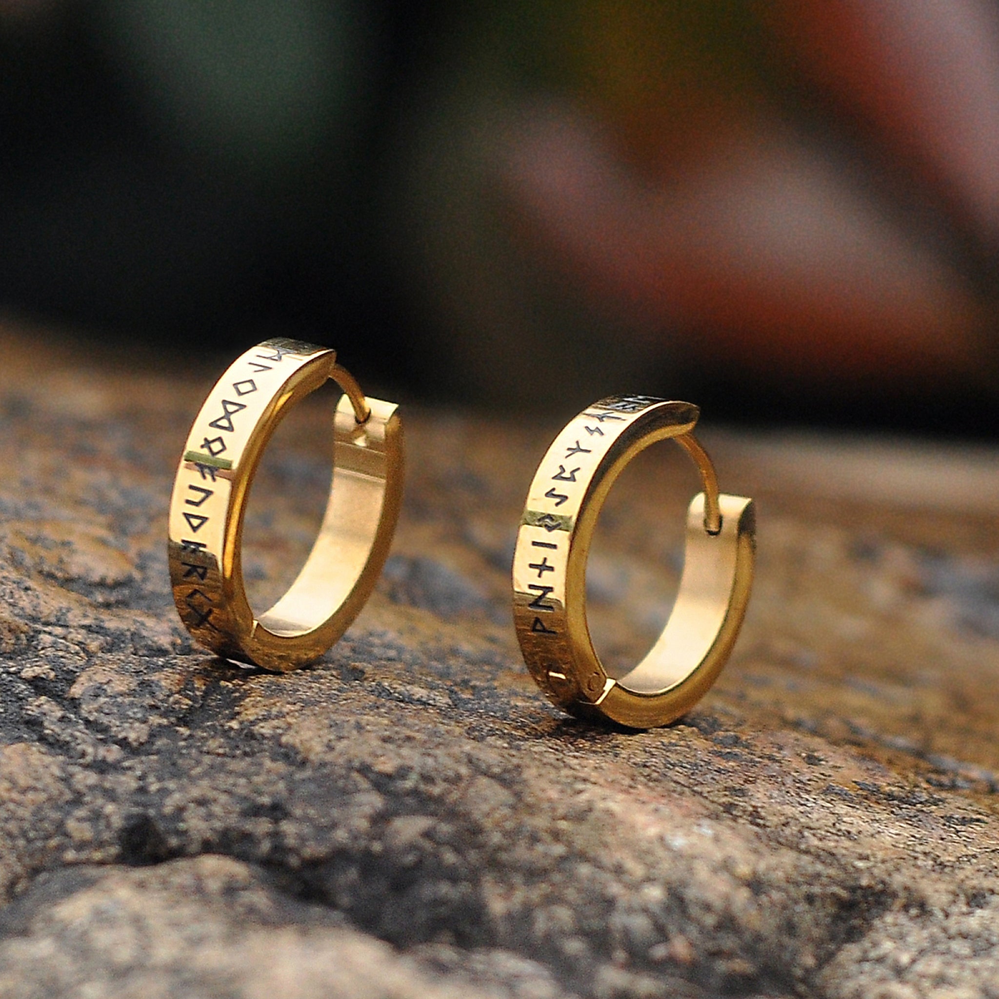 Guldfärgade runda örhängen med runor från den äldre futharken