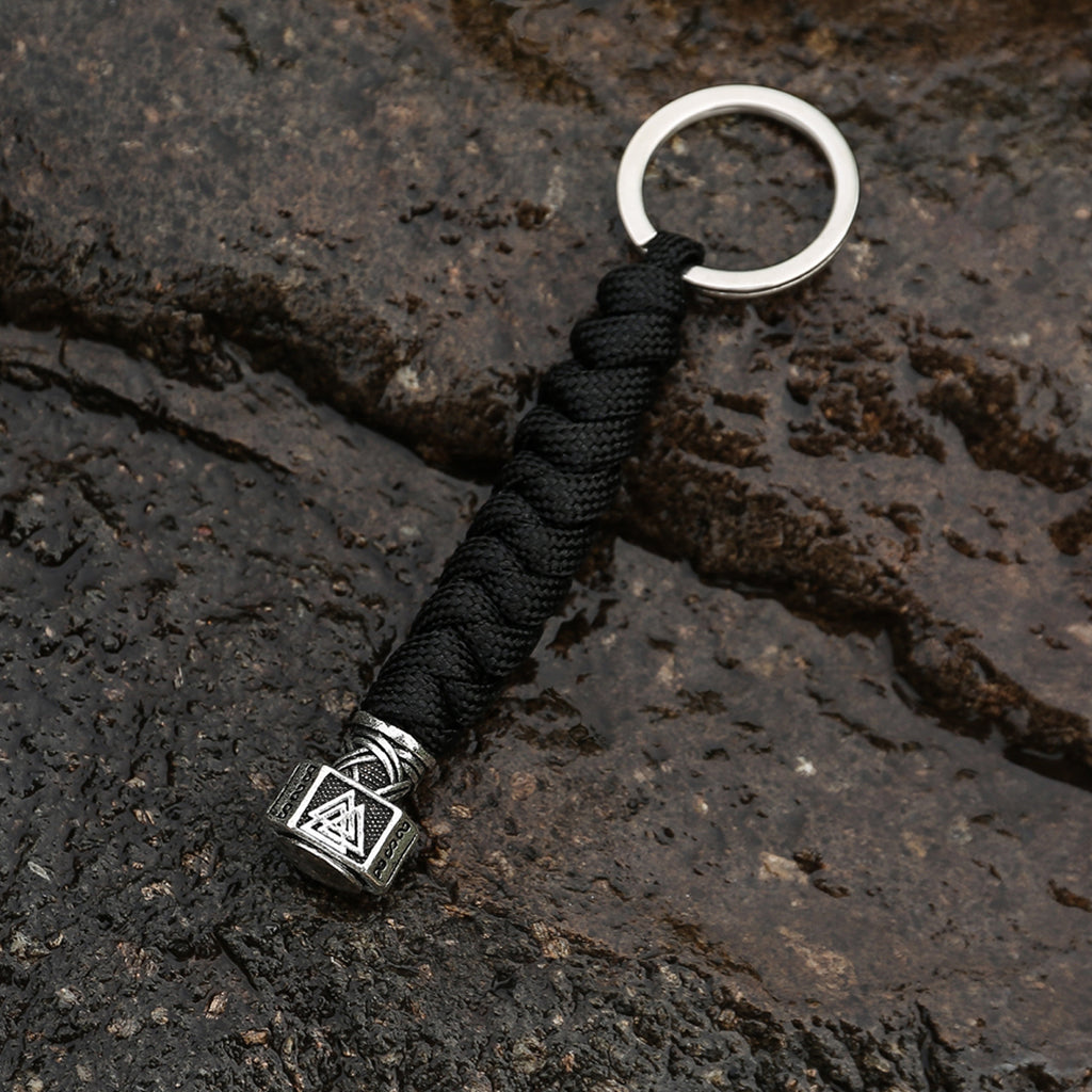 Silverfärgat Tors hammare smycke hängande i svart paracord