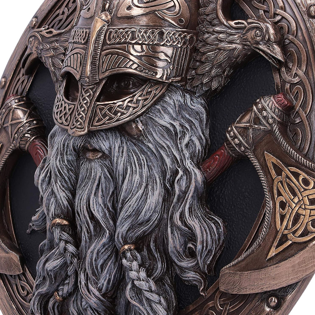 Vikingatida väggprydnad i form av asaguden Oden framför två korslagda skäggyxor