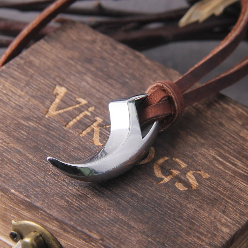 Smycke av rostfritt stål i form av en tand från en varg, upphängt i brunt läderband