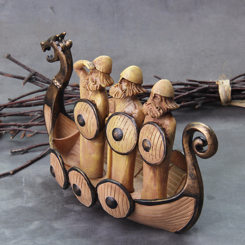Viking prydnadsskepp med drakhuvud framtill och tre vikingafigurer i båten
