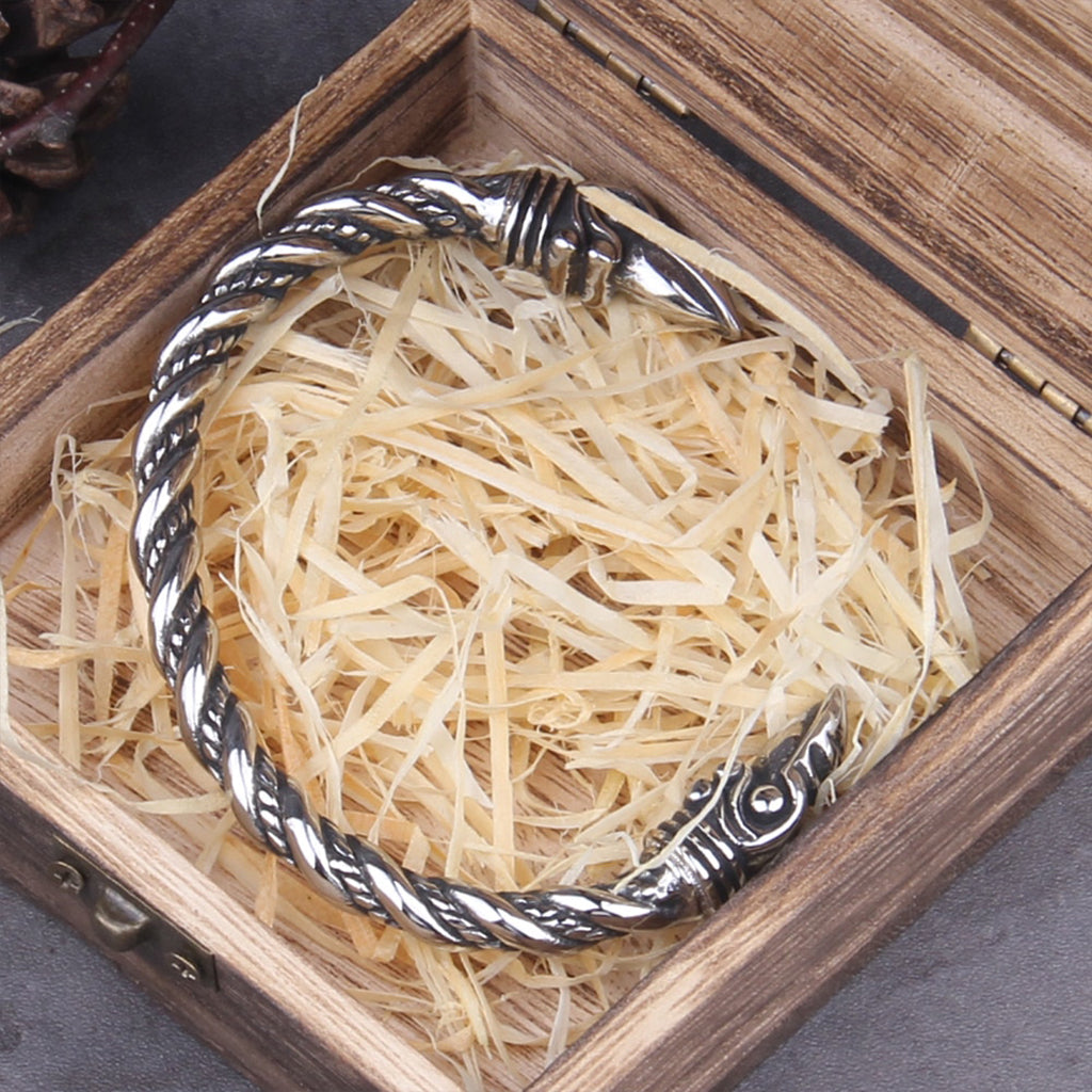 Silverfärgat vikinga armband dekorerat med korphuvuden som symboliserar Hugin och Munin
