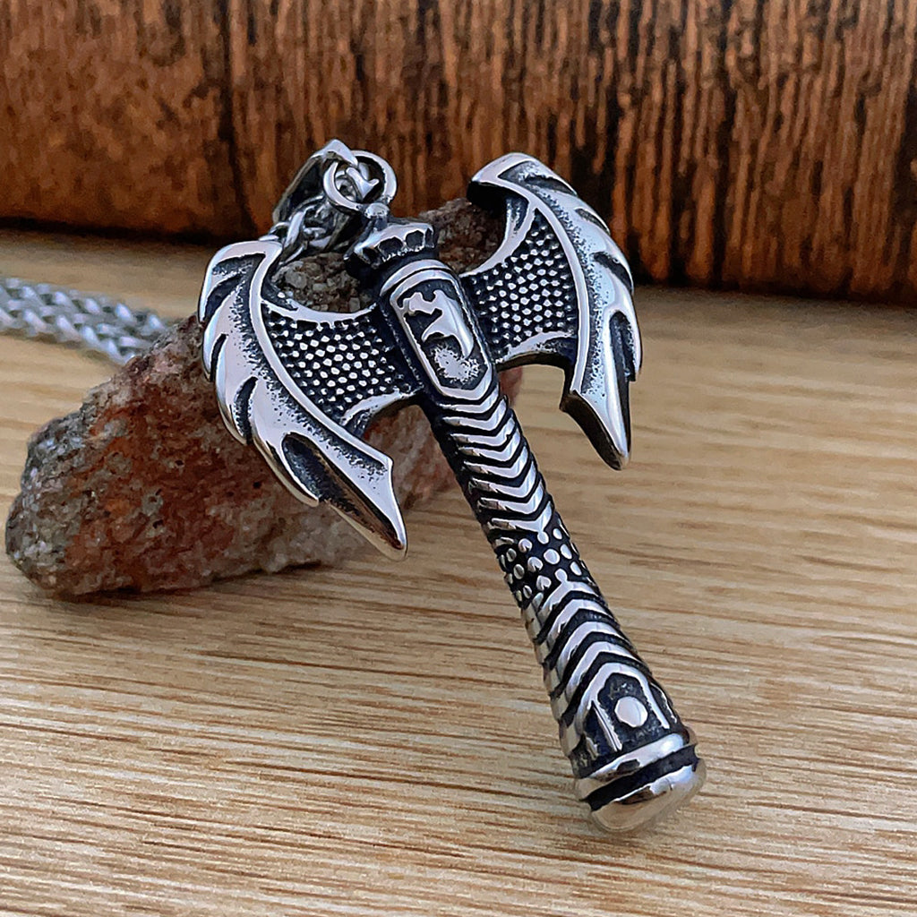 Silverfärgad dubbelyxa hängande i stålhalsband