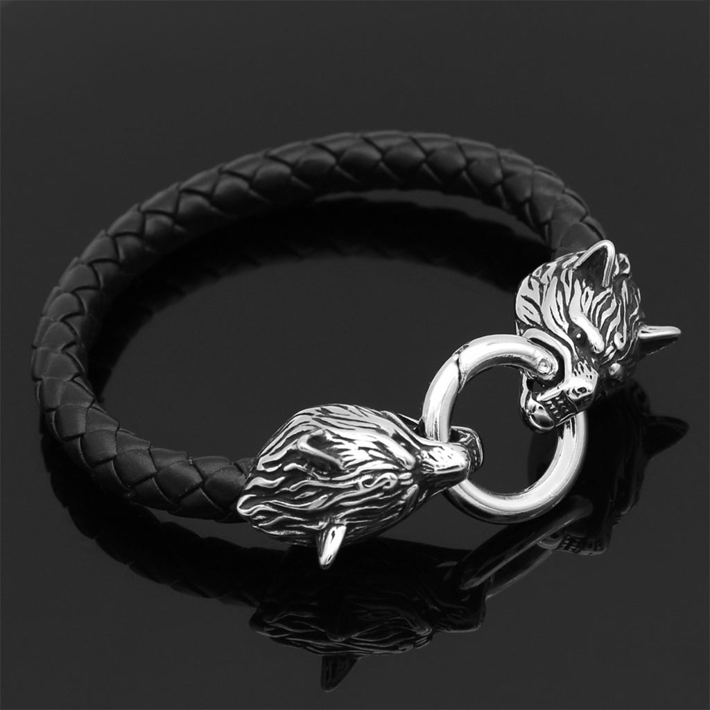 Svart läderarmband med silverfärgade gråvargar hållande en ring mellan tänderna