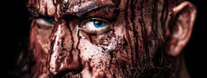 Närbild på blodig vikingakrigare med ljusblå ögon
