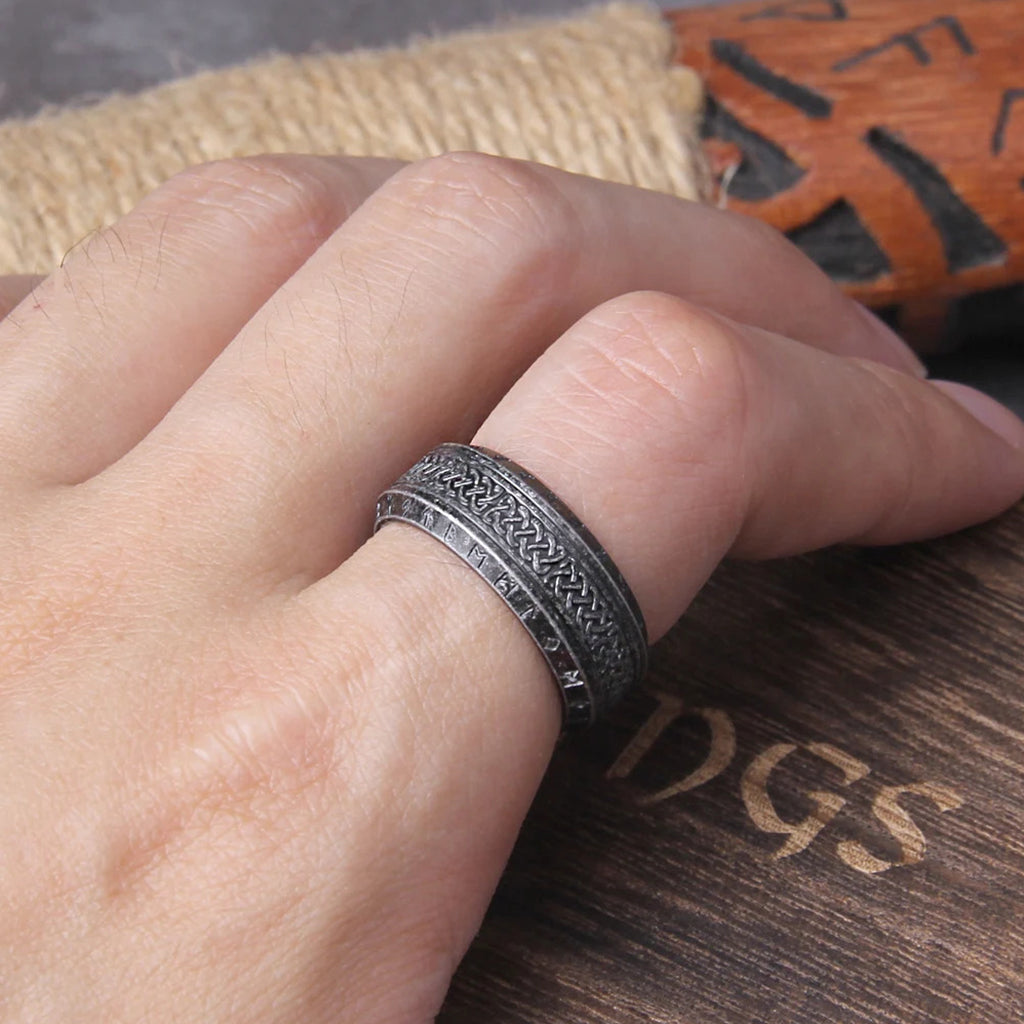 Gråsvart ring tillverkad av rostfritt stål, smyckad med vikingaknutar och runtecken