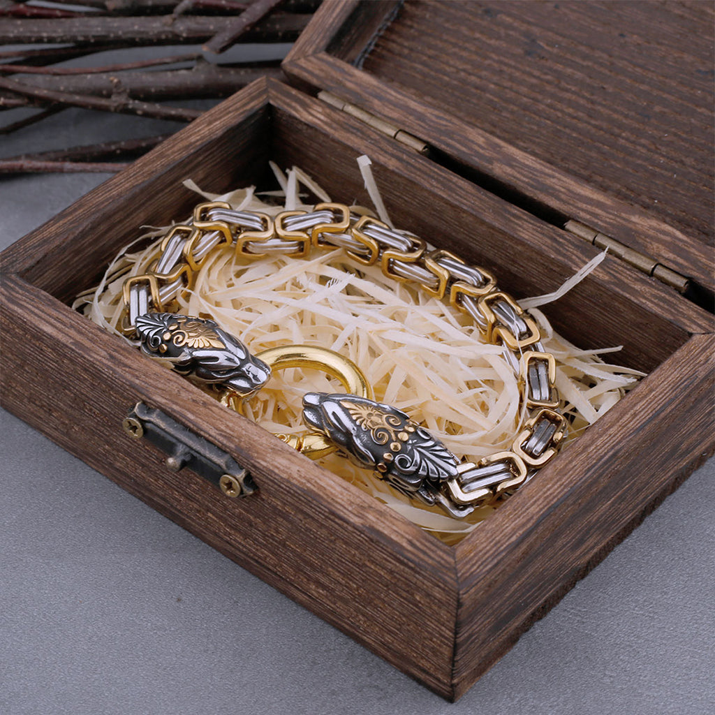 Stål- och guldfärgat armband med två skulpterade kattdjur hållande ring mellan varandra